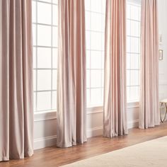 a living room filled with furniture and windows covered in light pink draping curtains