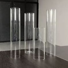 three tall clear vases sitting on top of a wooden table next to each other