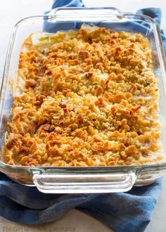 a casserole dish with meat and cheese in it on a blue cloth next to a fork