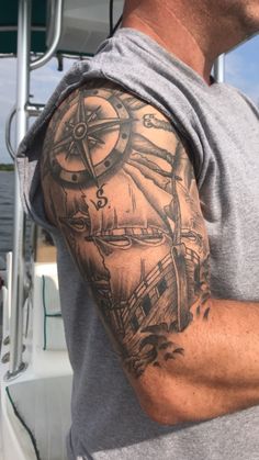 a man with a tattoo on his arm is standing in front of a boat and looking at the camera