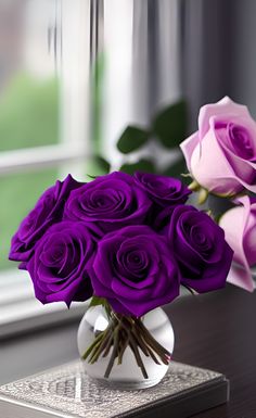 a vase filled with purple roses on top of a table