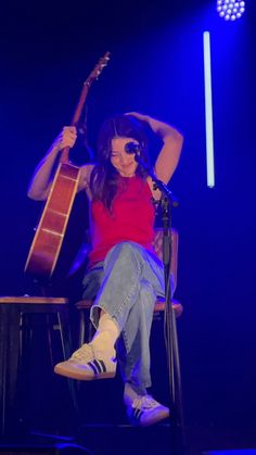 a woman sitting on top of a chair with a guitar in front of her face