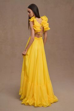 a woman wearing a yellow dress with ruffles on it