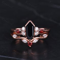 a black diamond ring with red and white stones on it's sides, sitting on a dark surface