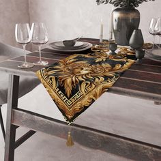 a table topped with a black and gold place mat next to a vase filled with flowers