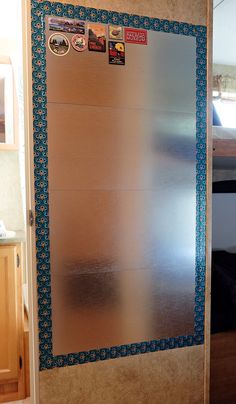 a metallic refrigerator freezer sitting inside of a kitchen next to a counter top with magnets on it