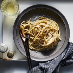 a plate of pasta with parmesan cheese on top and two spoons next to it