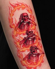 a person with a tattoo on their arm that has three skeletons in flames around them