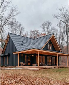 a large house with a metal roof in the middle of leaves on the ground and trees around it