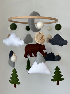 a mobile made out of felt and wood with bear, mountain, clouds, and pine trees