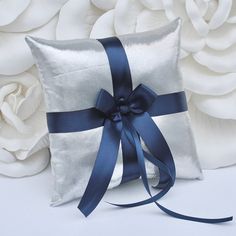 a white pillow with a blue ribbon on it and flowers in the backgroun