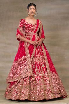 a woman in a red and gold lehenga with an intricate pattern on the skirt