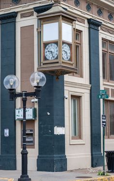 a clock tower on the corner of a street in front of a building with windows