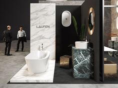 a man standing in front of a bathroom with black and white marble walls, flooring and furniture