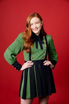 a young woman in a green and black dress posing for the camera with her hands on her hips