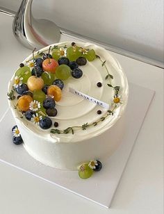 a white cake with fruit on it sitting on top of a table