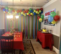 a party room with balloons and streamers on the wall, table set for two