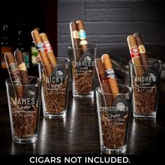 six shot glasses filled with cigars on top of a table