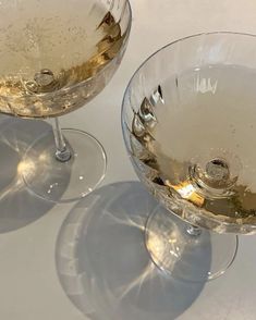 two empty wine glasses sitting on top of a white countertop next to each other