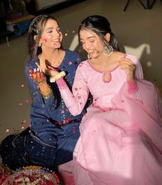 two women sitting next to each other and throwing confetti on them