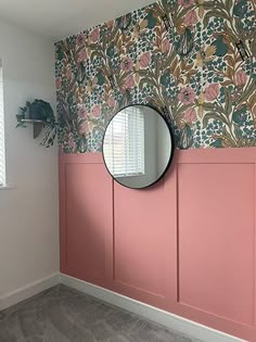 a mirror on the wall in a room with pink paneling and floral wallpaper