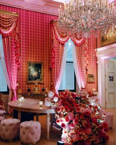 an elegant dining room decorated in pink and red colors with chandelier above the table