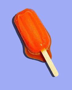 an orange popsicle with a wooden stick sticking out of it's center on a blue background