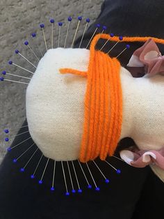 an orange and white stuffed animal with pins on it's head