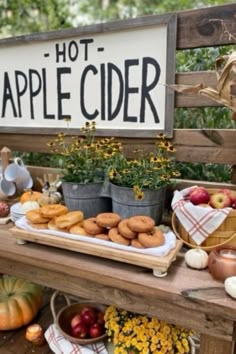 an apple cider stand with apples, donuts and other fruit on it's table