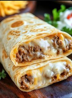 two burritos sitting on top of a wooden cutting board