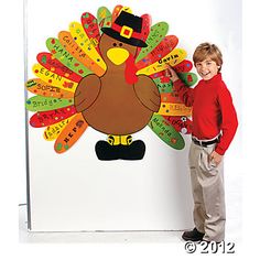 a young boy standing in front of a turkey cutout with words on it's face