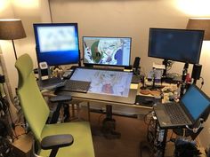 three computer monitors sitting on top of a desk next to two laptops and a monitor