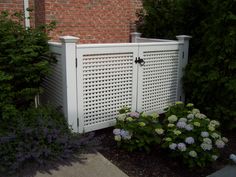 a white gate surrounded by flowers and bushes