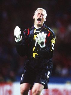 a soccer player with his mouth wide open and hands in the air as he celebrates