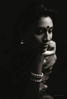 a black and white photo of a woman with her hand on her chin