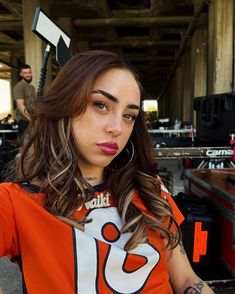 a woman with long hair wearing an orange and white shirt is posing for the camera