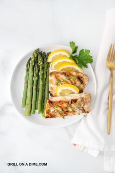 grilled chicken, asparagus and lemon slices on a plate with a fork