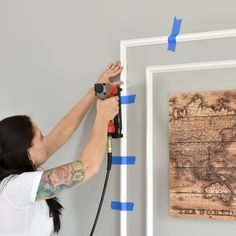 a woman is using a drill to paint a map on the wall