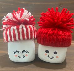 two red and white knitted cups with faces on them