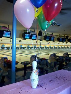 a bowling alley filled with bowling balls and balloons in front of an empty bowling alley