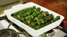 a white dish filled with green vegetables on top of a stove