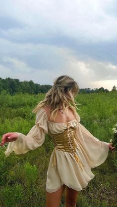 a woman in a dress is walking through the grass