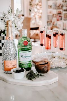 bottles of wine and glasses on a marble table with flowers in the backgroud