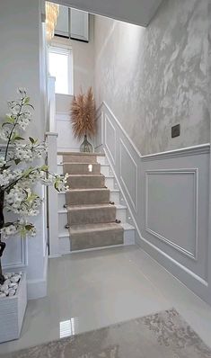 a white staircase leading up to the second floor with flowers in vases on either side