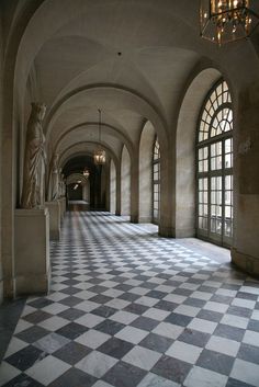 an empty hallway with checkered tile floors and chandelier hanging from the ceiling