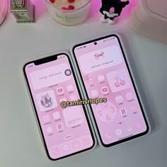 two pink iphones sitting next to each other on a white table with candy in the background