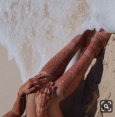 two women covered in henna laying on the beach