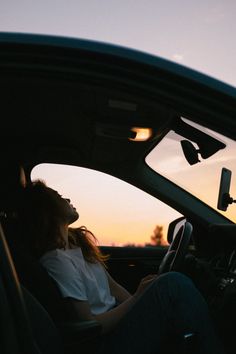 a woman sitting in the driver's seat of a car with her eyes closed