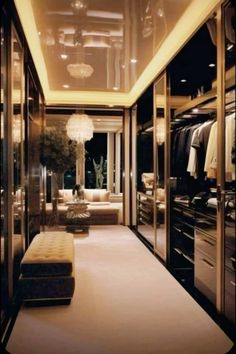 a large walk in closet with lots of clothes on hangers and lights hanging from the ceiling