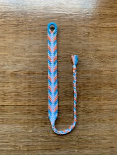 a blue, orange and white lanyard sitting on top of a wooden table next to an umbrella